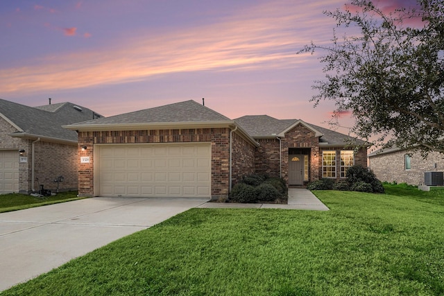 view of front of property with a garage, a yard, and central AC unit