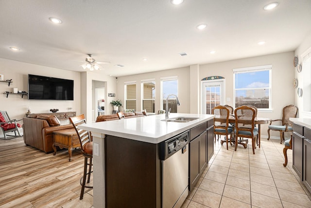 kitchen with sink, stainless steel dishwasher, ceiling fan, dark brown cabinets, and a center island with sink