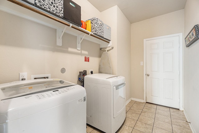 clothes washing area with light tile patterned floors and washer and clothes dryer