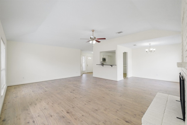 unfurnished living room featuring lofted ceiling, a brick fireplace, ceiling fan with notable chandelier, and light wood-type flooring