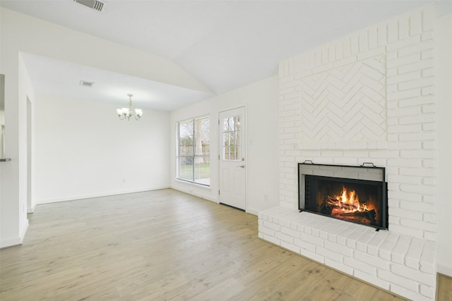 unfurnished living room featuring lofted ceiling, hardwood / wood-style flooring, a fireplace, and a chandelier