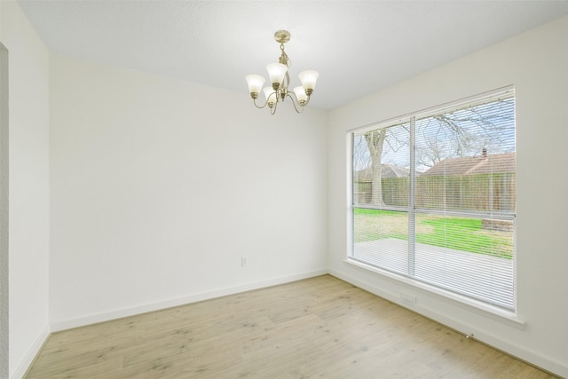 unfurnished room with an inviting chandelier and light wood-type flooring