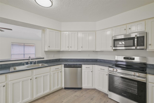 kitchen featuring stainless steel appliances, sink, light hardwood / wood-style flooring, and white cabinets