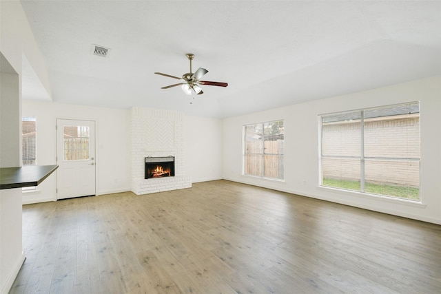 unfurnished living room with a brick fireplace, a healthy amount of sunlight, and light hardwood / wood-style floors