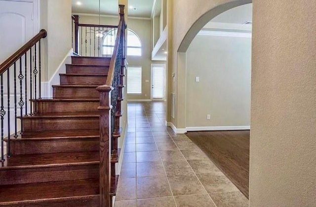 stairs featuring crown molding, a towering ceiling, and tile patterned floors