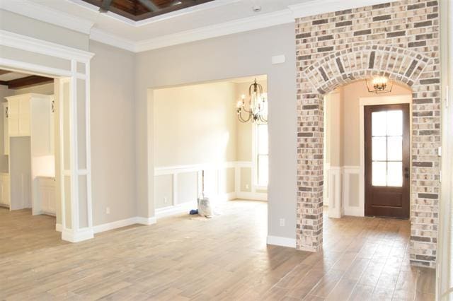 entrance foyer featuring hardwood / wood-style flooring, crown molding, and a chandelier