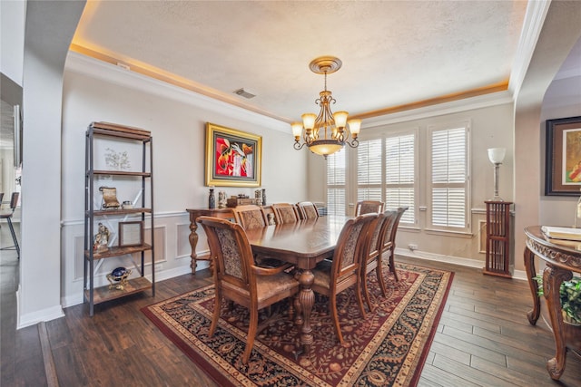 dining space with a raised ceiling, ornamental molding, and dark hardwood / wood-style flooring