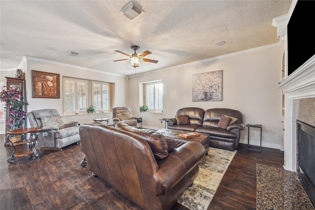 living room featuring dark wood-type flooring, ceiling fan, ornamental molding, and a textured ceiling