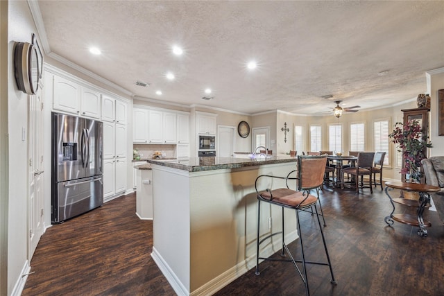 kitchen with a breakfast bar, white cabinetry, black microwave, a center island, and stainless steel refrigerator with ice dispenser