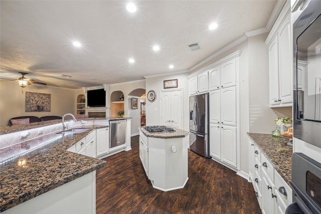 kitchen with sink, appliances with stainless steel finishes, white cabinetry, dark stone countertops, and a kitchen island