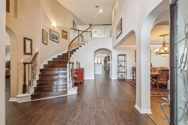 foyer featuring a towering ceiling, a notable chandelier, and dark hardwood / wood-style flooring