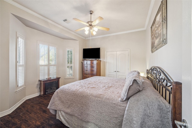 bedroom featuring crown molding, dark wood-type flooring, ceiling fan, and a closet