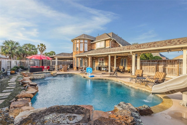 view of pool featuring a fire pit, a patio area, an in ground hot tub, and a water slide