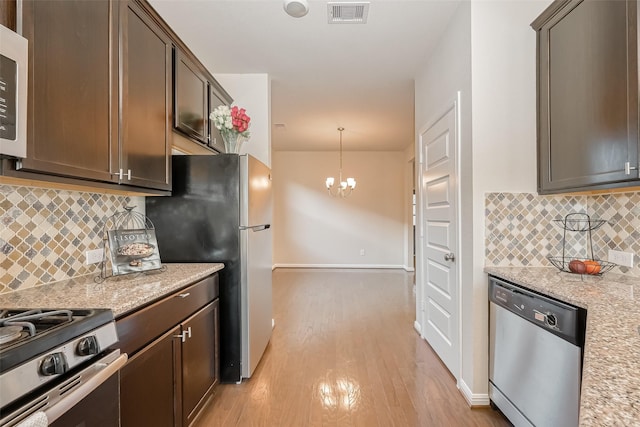 kitchen featuring appliances with stainless steel finishes, decorative light fixtures, light hardwood / wood-style floors, dark brown cabinetry, and light stone countertops