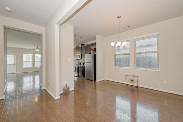 unfurnished dining area featuring dark hardwood / wood-style flooring and ceiling fan with notable chandelier