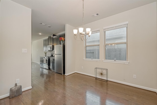 unfurnished dining area featuring an inviting chandelier and dark hardwood / wood-style floors