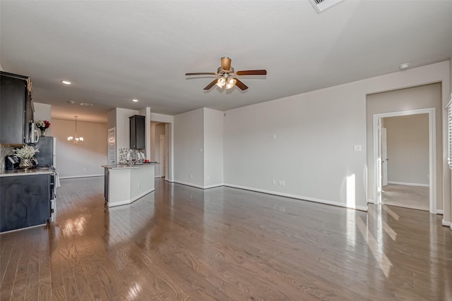 unfurnished living room featuring ceiling fan with notable chandelier and dark hardwood / wood-style flooring