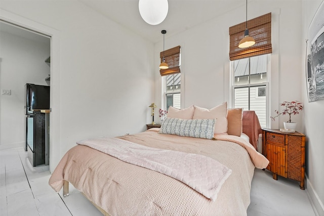 bedroom featuring multiple windows and black refrigerator