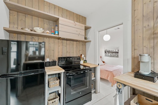 kitchen featuring butcher block counters, decorative light fixtures, black appliances, and wood walls