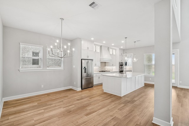 20406 Magnolia Flint Dr, Cypress, TX 77433 - kitchen featuring stainless steel appliances, custom range hood, a chandelier, light countertops, and light wood-style flooring