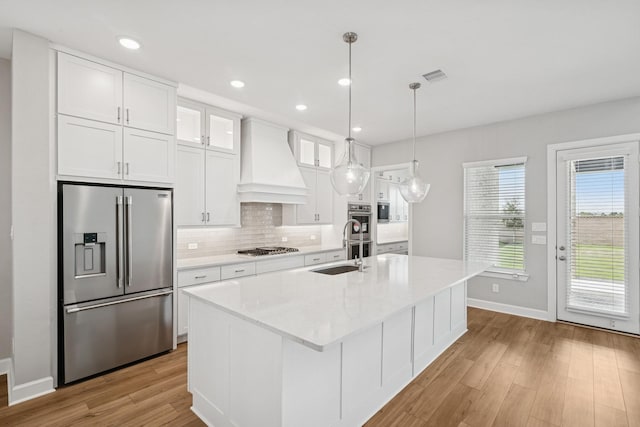 20406 Magnolia Flint Dr, Cypress, TX 77433 - kitchen featuring stainless steel appliances, custom exhaust hood, tasteful backsplash, light wood finished floors, and white cabinets
