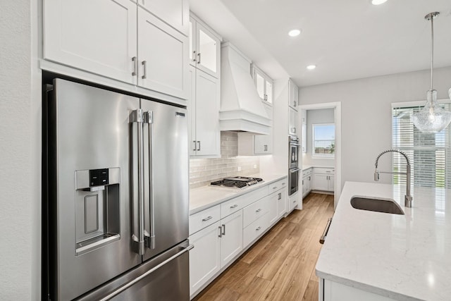 20406 Magnolia Flint Dr, Cypress, TX 77433 - kitchen featuring stainless steel appliances, tasteful backsplash, white cabinetry, custom range hood, and light wood-style flooring