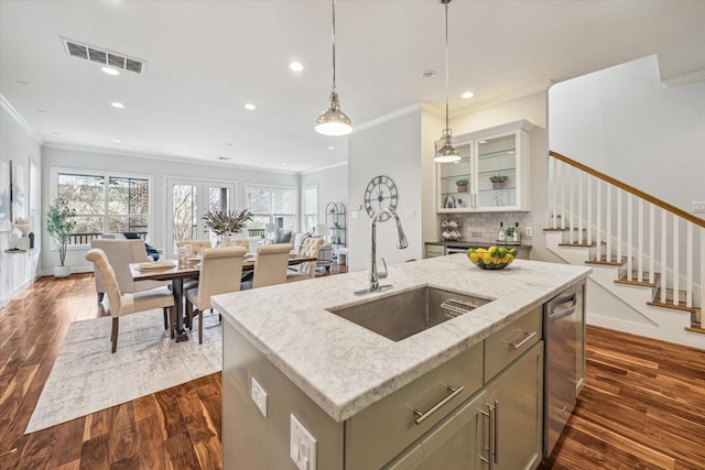 kitchen featuring sink, dark hardwood / wood-style floors, light stone countertops, an island with sink, and decorative light fixtures