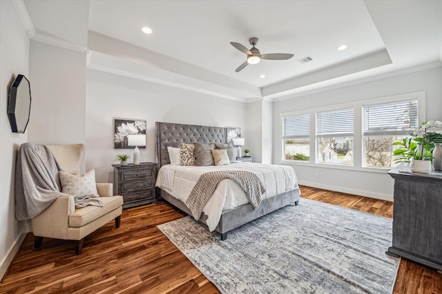 bedroom with dark wood-type flooring, ceiling fan, crown molding, and a raised ceiling