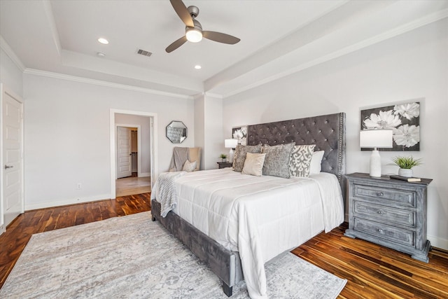 bedroom featuring dark hardwood / wood-style floors, ceiling fan, a tray ceiling, and crown molding