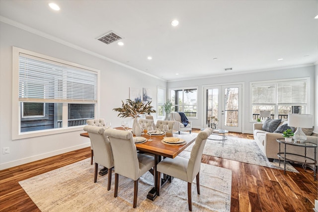 dining space with hardwood / wood-style flooring, ornamental molding, and french doors