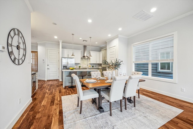 dining area with hardwood / wood-style flooring, ornamental molding, and sink