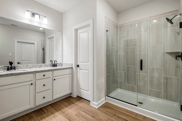 bathroom with wood-type flooring, a shower with door, and vanity