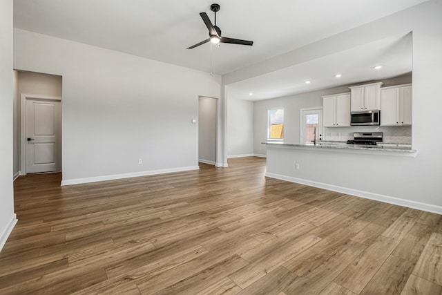 unfurnished living room with ceiling fan, sink, and light wood-type flooring