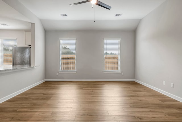 unfurnished room with wood-type flooring, vaulted ceiling, and a healthy amount of sunlight