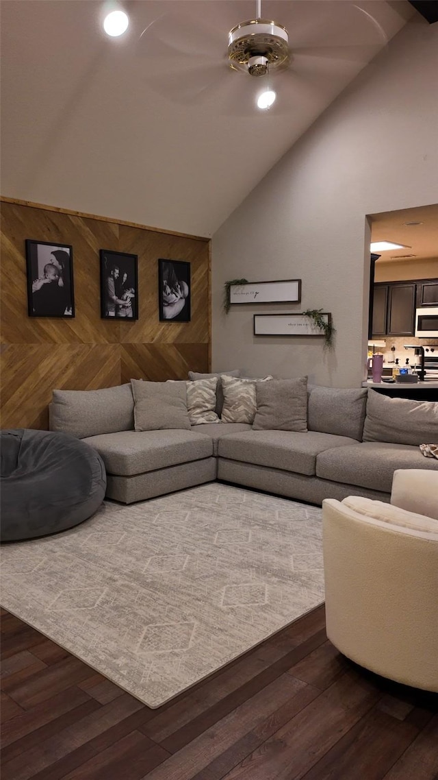 living room featuring high vaulted ceiling, dark wood-type flooring, and wooden walls