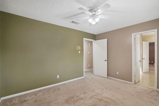 unfurnished bedroom featuring ceiling fan, light colored carpet, and a textured ceiling