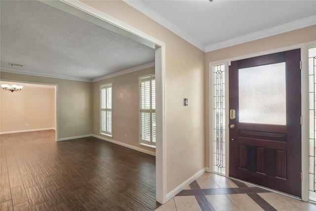 foyer featuring hardwood / wood-style floors, a notable chandelier, ornamental molding, and a textured ceiling