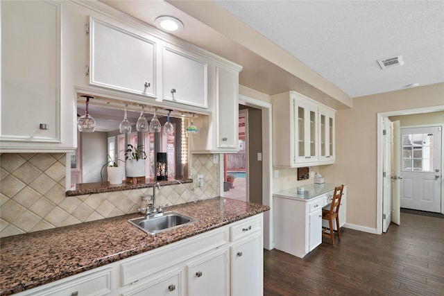 kitchen with sink, white cabinetry, a textured ceiling, dark stone countertops, and dark hardwood / wood-style flooring