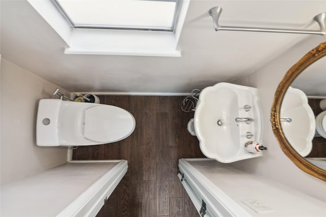 bathroom with hardwood / wood-style floors and a skylight