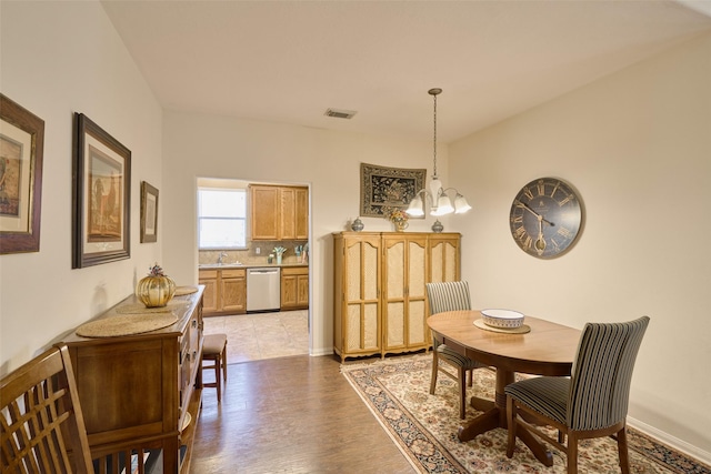 dining room featuring sink, hardwood / wood-style flooring, and a notable chandelier