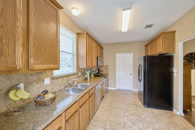 kitchen with sink, tasteful backsplash, stone counters, appliances with stainless steel finishes, and light tile patterned flooring