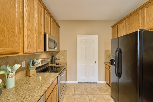 kitchen featuring appliances with stainless steel finishes, tasteful backsplash, light stone counters, and light tile patterned floors