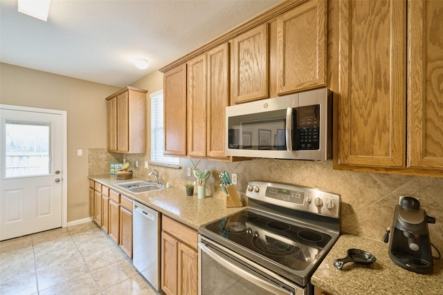 kitchen featuring appliances with stainless steel finishes, sink, a wealth of natural light, and light stone counters