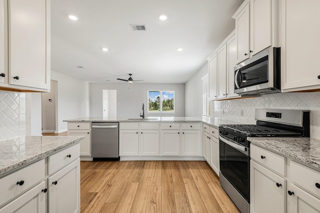 kitchen featuring sink, light hardwood / wood-style flooring, stainless steel appliances, light stone countertops, and white cabinets