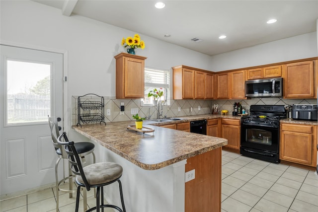 kitchen with sink, light tile patterned floors, a kitchen breakfast bar, kitchen peninsula, and black appliances