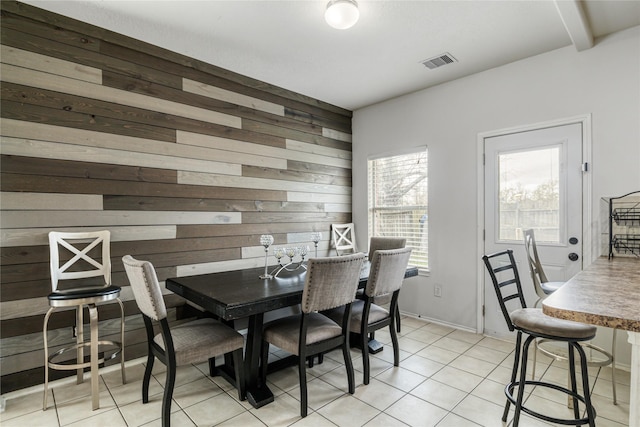 dining area featuring light tile patterned floors and wood walls