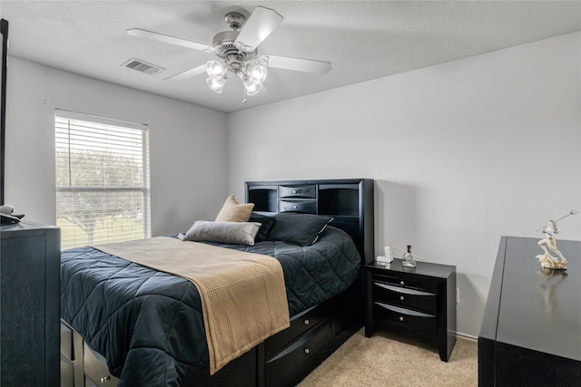 bedroom featuring ceiling fan, light carpet, and a textured ceiling