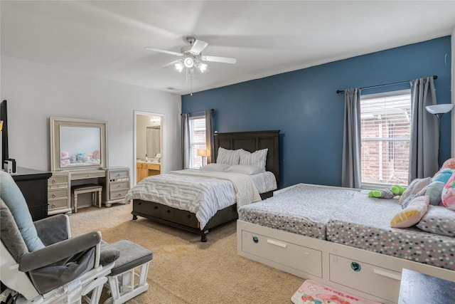 bedroom featuring multiple windows, light carpet, ceiling fan, and ensuite bathroom