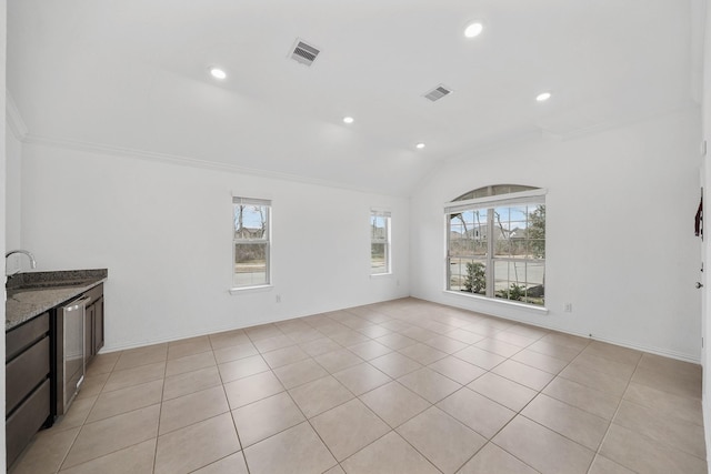 unfurnished living room with vaulted ceiling, ornamental molding, sink, and light tile patterned floors