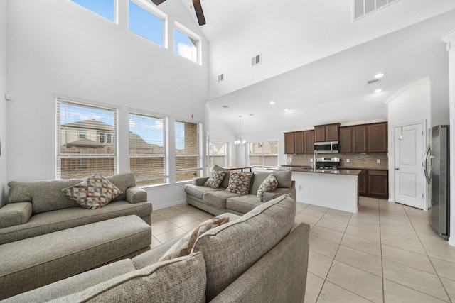 living room featuring a high ceiling, a wealth of natural light, light tile patterned floors, and a chandelier